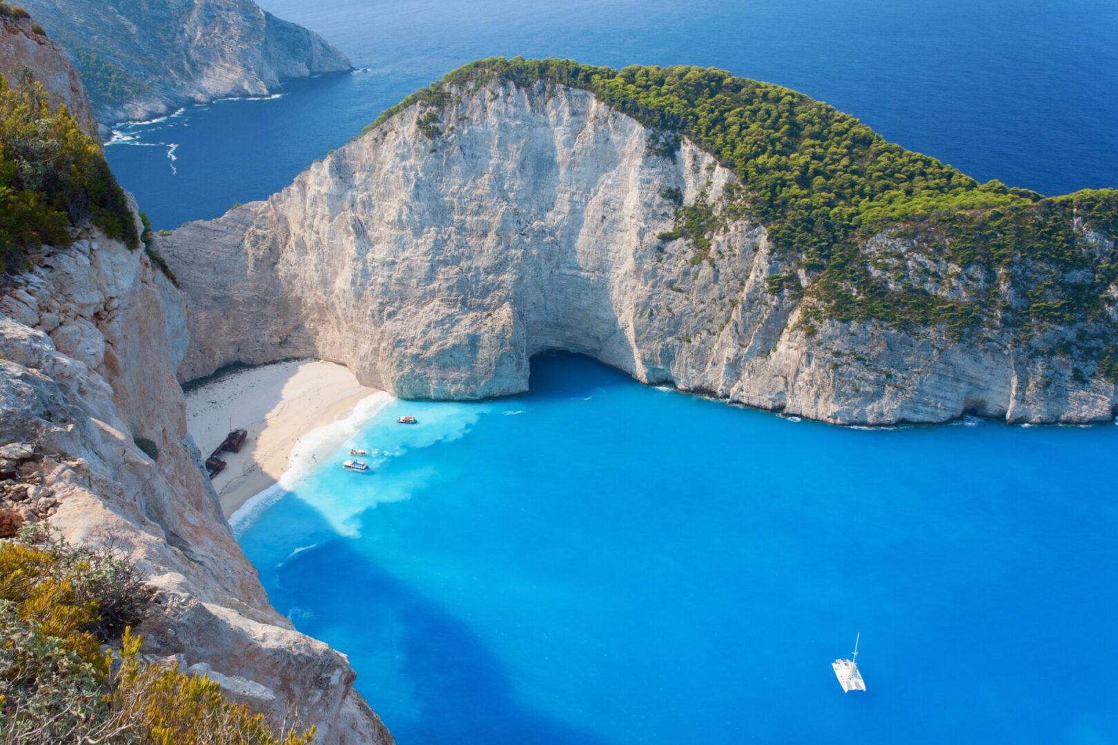 Cliffside beach with turquoise water and boat.